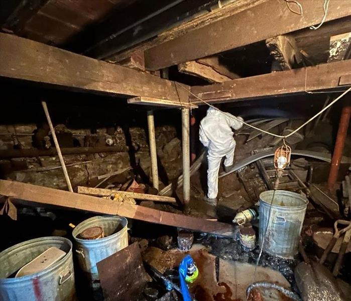 Technician in heavily soiled crawlspace preparing for water extraction